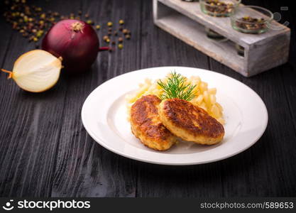 Delicious meatballs cutlets with garnish on black rustic wooden background.