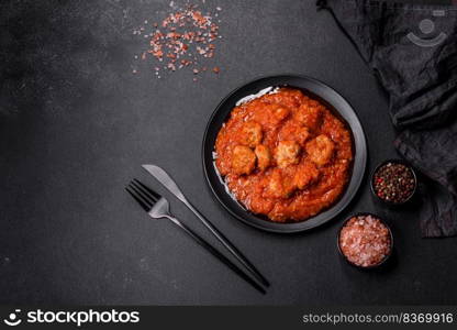 Delicious meatballs made from ground beef in a spicy tomato sauce served in a black pan. Delicious meatballs made from ground beef in a spicy tomato sauce