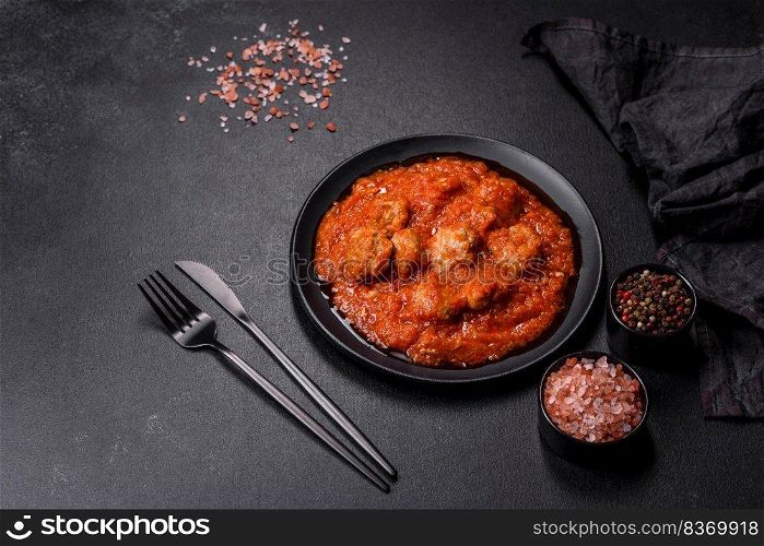 Delicious meatballs made from ground beef in a spicy tomato sauce served in a black pan. Delicious meatballs made from ground beef in a spicy tomato sauce