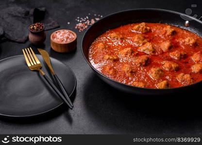 Delicious meatballs made from ground beef in a spicy tomato sauce served in a black pan. Delicious meatballs made from ground beef in a spicy tomato sauce