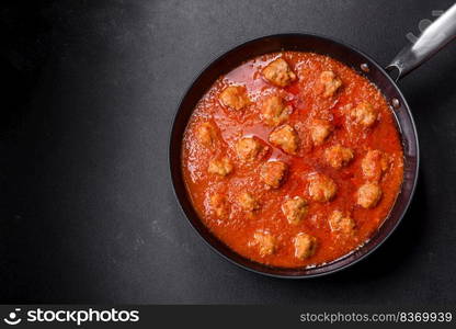 Delicious meatballs made from ground beef in a spicy tomato sauce served in a black pan. Delicious meatballs made from ground beef in a spicy tomato sauce