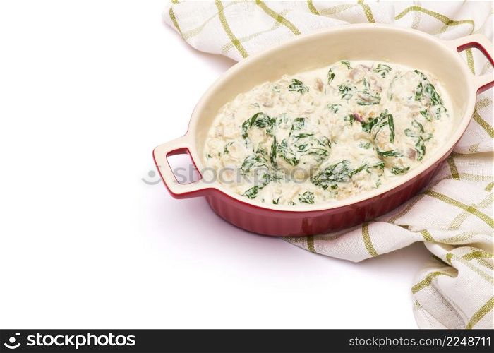 Delicious meatballs with spinach in a creamy sauce in baking dish on white background. High quality photo. Delicious meatballs with spinach in a creamy sauce in baking dish on white background