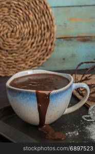 Delicious melted chocolate sauce in mug with whisk on table.
