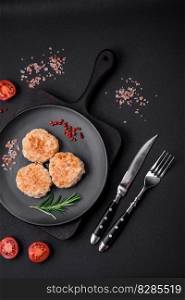 Delicious minced chicken cutlets with spices and herbs on a black ceramic plate