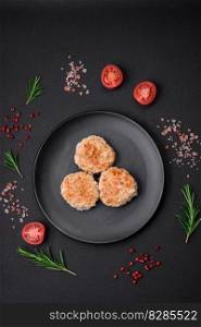 Delicious minced chicken cutlets with spices and herbs on a black ceramic plate