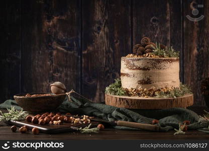 Delicious naked chocolate and hazelnuts cake on table rustic wood kitchen countertop.