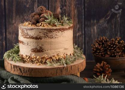Delicious naked chocolate and hazelnuts cake on table rustic wood kitchen countertop.
