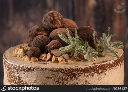 Delicious naked chocolate and hazelnuts cake on table rustic wood kitchen countertop.