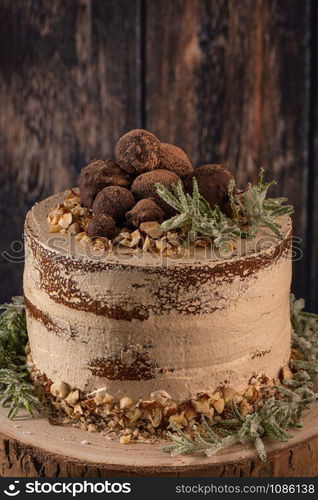 Delicious naked chocolate and hazelnuts cake on table rustic wood kitchen countertop.