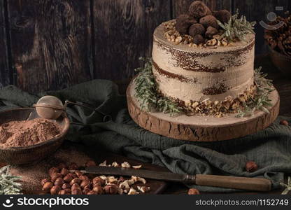 Delicious naked chocolate and hazelnuts cake on table rustic wood kitchen countertop.