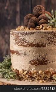 Delicious naked chocolate and hazelnuts cake on table rustic wood kitchen countertop.