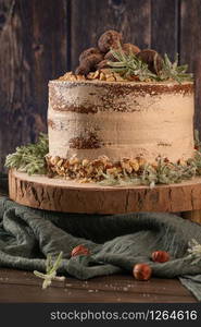 Delicious naked chocolate and hazelnuts cake on table rustic wood kitchen countertop.