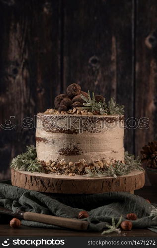 Delicious naked chocolate and hazelnuts cake on table rustic wood kitchen countertop.