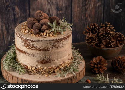 Delicious naked chocolate and hazelnuts cake on table rustic wood kitchen countertop.