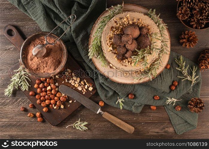 Delicious naked chocolate and hazelnuts cake on table rustic wood kitchen countertop. Top view. Flat lay.