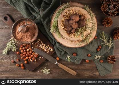 Delicious naked chocolate and hazelnuts cake on table rustic wood kitchen countertop. Top view. Flat lay.