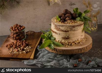 Delicious naked coffee and hazelnuts cake on table rustic wood kitchen countertop.