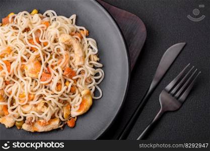 Delicious noodles with chicken and vegetables or udon on a black ceramic plate on a dark concrete background