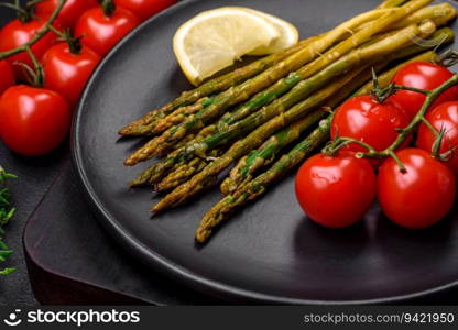 Delicious nutritious breakfast consisting of asparagus, tomatoes, salt, spices and herbs on a dark concrete background