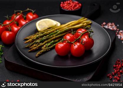 Delicious nutritious breakfast consisting of asparagus, tomatoes, salt, spices and herbs on a dark concrete background