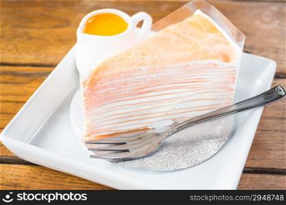 Delicious orange crepe cake serving on the plate, stock photo