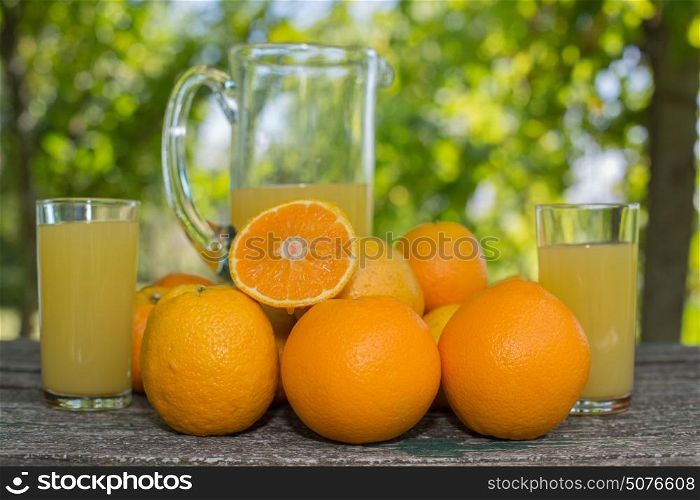 delicious orange juice and oranges on table in garden