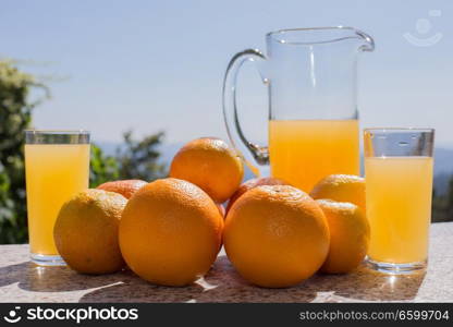 delicious orange juice and oranges on table in garden