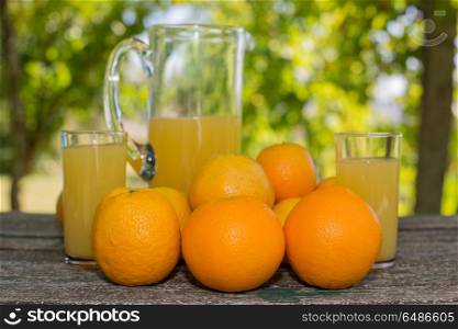 delicious orange juice and oranges on table in garden. orange juice