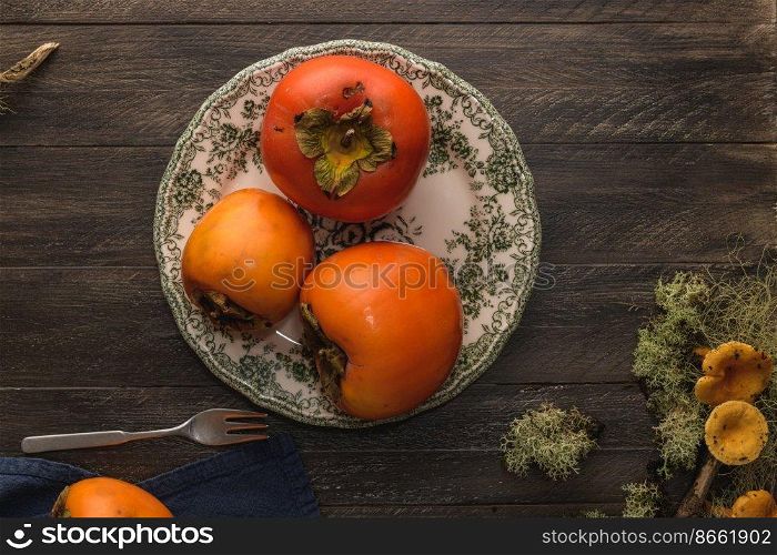 Delicious orange persimmons on wooden table.