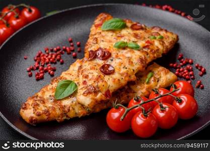 Delicious oven fresh flatbread pizza with cheese, tomatoes, sausage, salt and spices on a dark concrete background