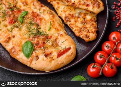 Delicious oven fresh flatbread pizza with cheese, tomatoes, sausage, salt and spices on a dark concrete background