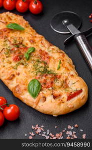 Delicious oven fresh flatbreadπzza with cheese, tomatoes, sausa≥, sa<and sπces on a dark concrete background