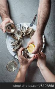Delicious oysters with slice of lemon and glasses of white wine, top view. Exotic dish - oysters with wine