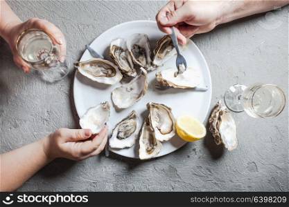 Delicious oysters with slice of lemon and glasses of white wine, top view. Exotic dish - oysters with wine