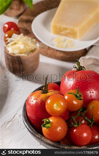 Delicious parmesan cheese, tomato and basil. Fresh ingredients for cooking pasta or sauce. Italian cuisine concept.