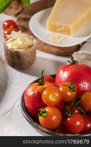 Delicious parmesan cheese, tomato and basil. Fresh ingredients for cooking pasta or sauce. Italian cuisine concept.