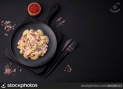 Delicious pasta with bacon and parmesan cheese on a black ceramic plate on a dark concrete background. Italian cuisine dish