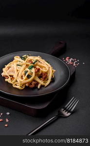 Delicious pasta with spinach, sun dried tomatoes, cheese, onions, spices and herbs on a dark concrete background