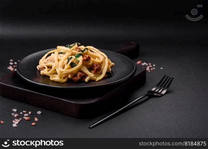 Delicious pasta with spinach, sun dried tomatoes, cheese, onions, spices and herbs on a dark concrete background