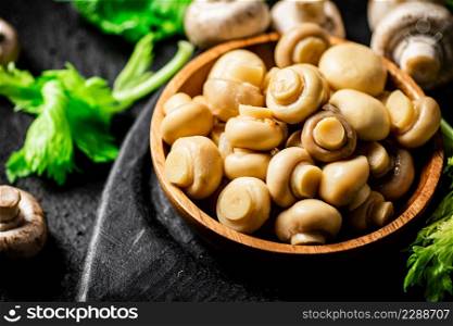 Delicious pickled mushrooms on a cutting board. On a black background. High quality photo. Delicious pickled mushrooms on a cutting board.