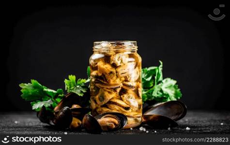 Delicious pickled mussels with parsley on the table. On a black background. High quality photo. Delicious pickled mussels with parsley on the table.