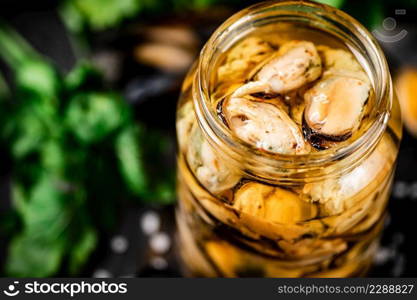 Delicious pickled mussels with parsley on the table. On a black background. High quality photo. Delicious pickled mussels with parsley on the table. 
