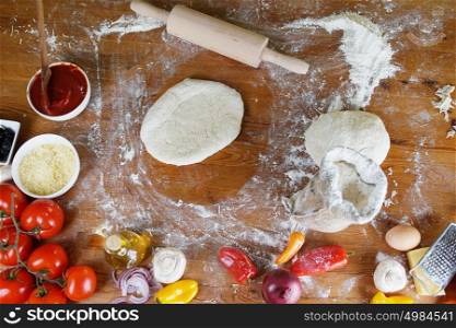 Delicious pizza dough, spices and vegetables on wooden table