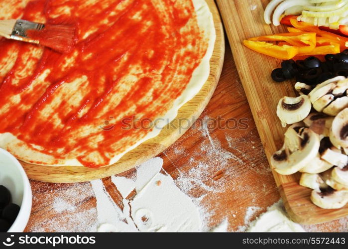 delicious pizza dough, spices and vegetables on wooden table