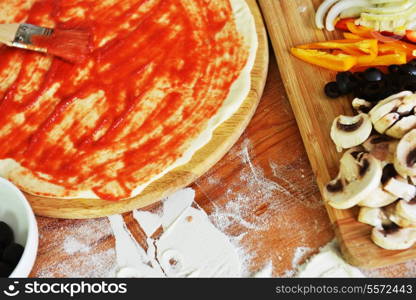 delicious pizza dough, spices and vegetables on wooden table