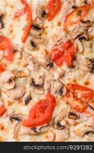Delicious pizza with chicken, tomatoes and cheese with salt and sauce on a dark concrete background