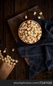 Delicious popcorn with caramel on wooden background.