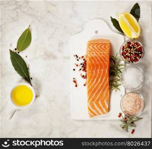 Delicious portion of fresh salmon fillet with aromatic herbs and spices - healthy food, diet or cooking concept. Top view.