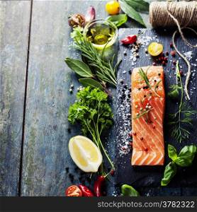 Delicious portion of fresh salmon fillet with aromatic herbs, spices and vegetables - healthy food, diet or cooking concept