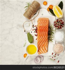 Delicious portion of fresh salmon fillet with aromatic herbs, spices and vegetables - healthy food, diet or cooking concept. Top view.